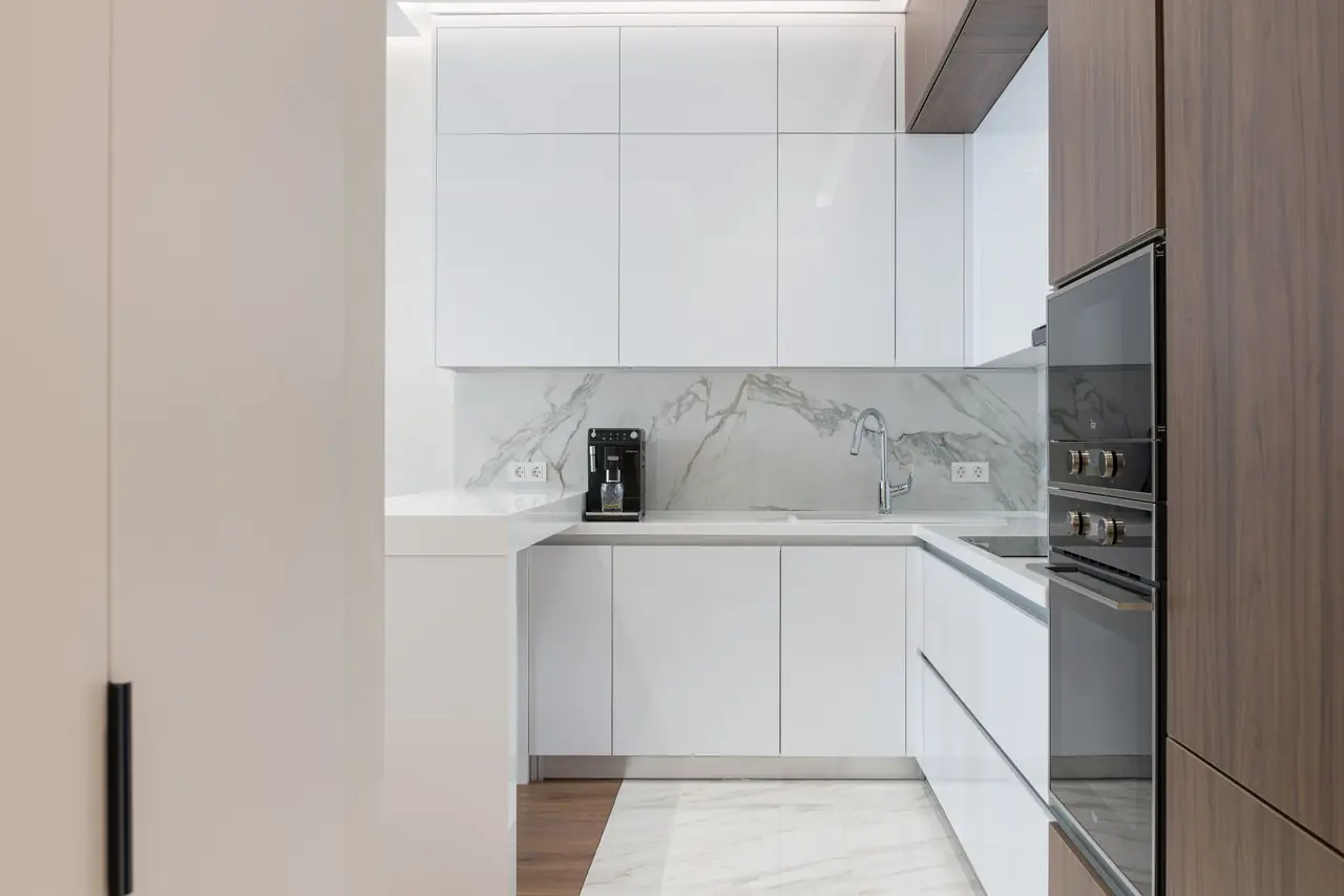 Balta minimalistinė virtuvė su marmuro imitacijos sienele